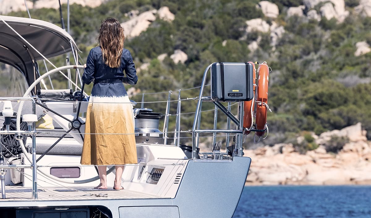 A guest at the stern rail of Sailing Yacht Freebird at anchor